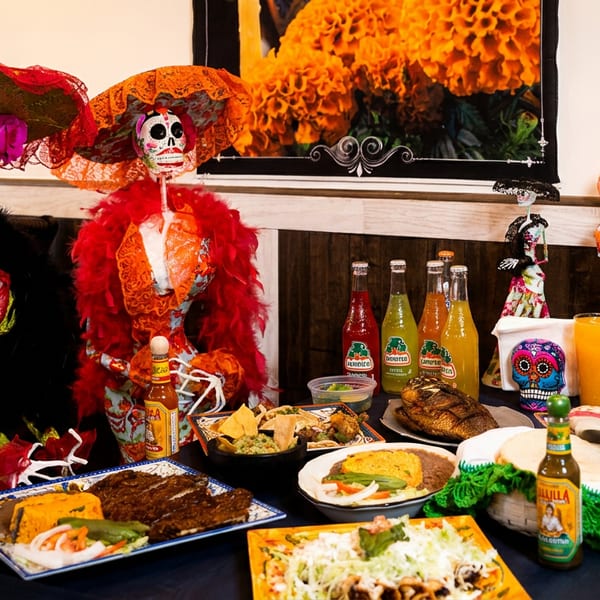 A table laden with Mexican food, drinks, and Day of the Dead skeleton decorations.